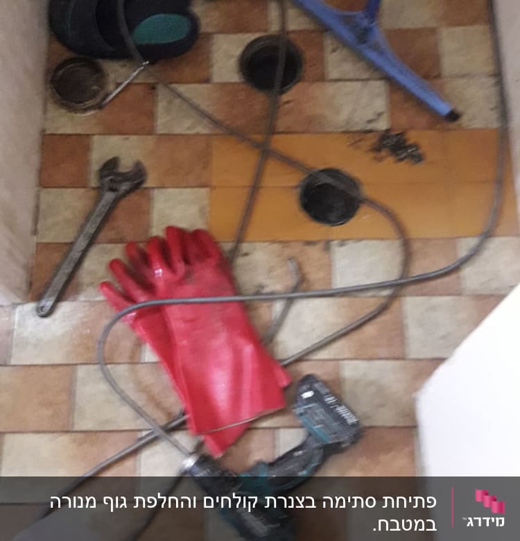 כלי עבודה של אינסטלטור על רצפה, כולל מקדחה וכפפות.